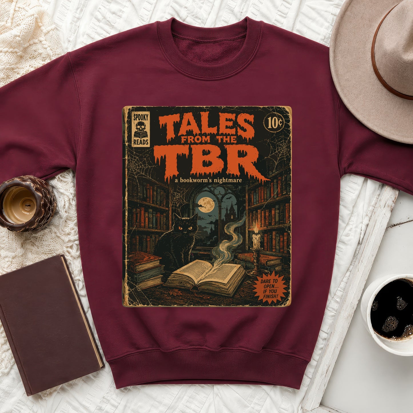 Burgundy crewneck sweatshirt featuring "Tales From The TBR" comic book art with a black cat.