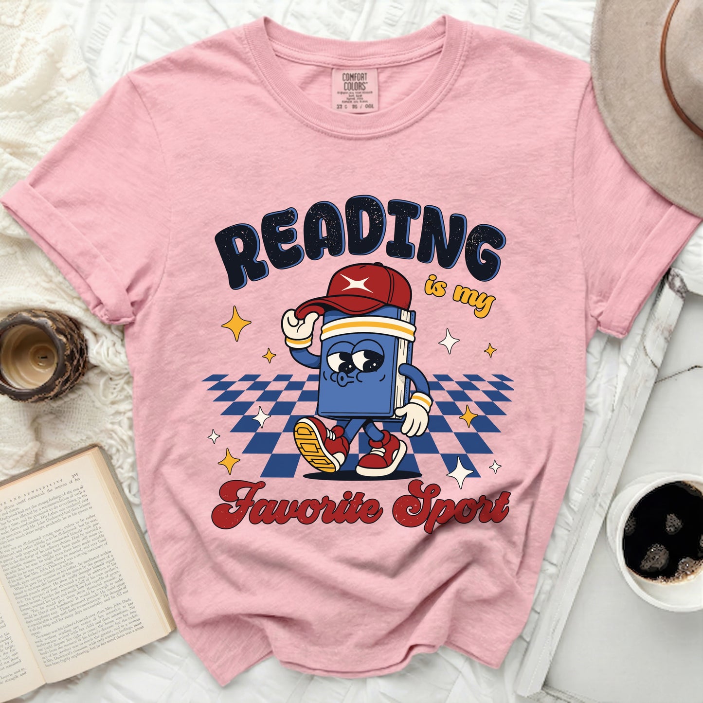 Pink t-shirt with cartoon book graphic that says "Reading is my favorite sport".