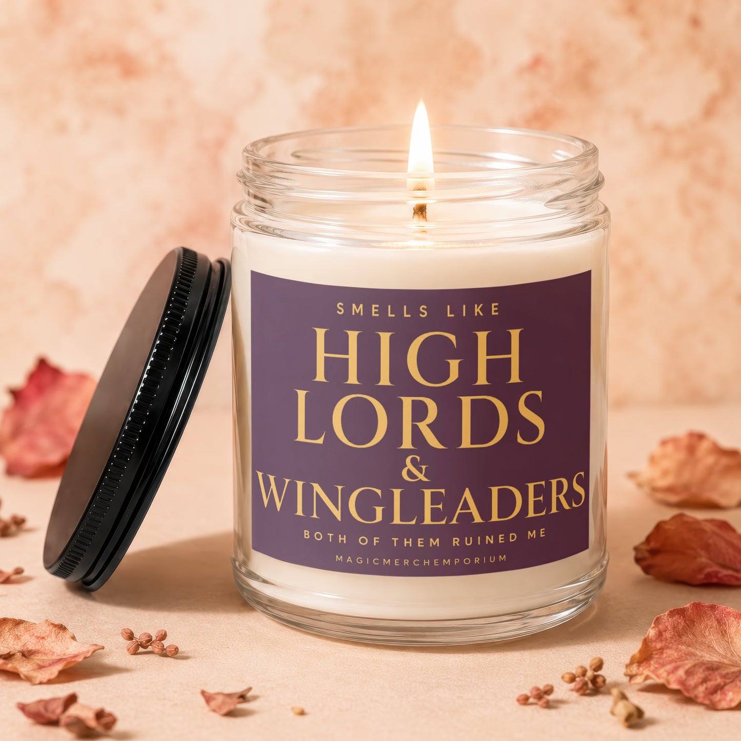 Glass candle with lit wick and purple label reading "Smells Like High Lords & Wingleaders".