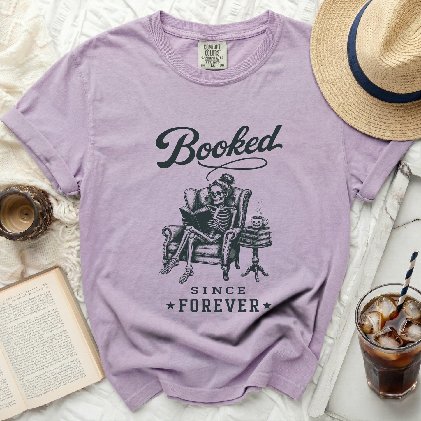 Lavender t-shirt with "Booked Since Forever" graphic of skeleton reading