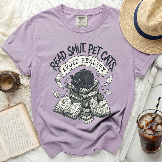 Purple t-shirt with graphic of black cat on books, text "Read Smut. Pet Cats. Avoid Reality."