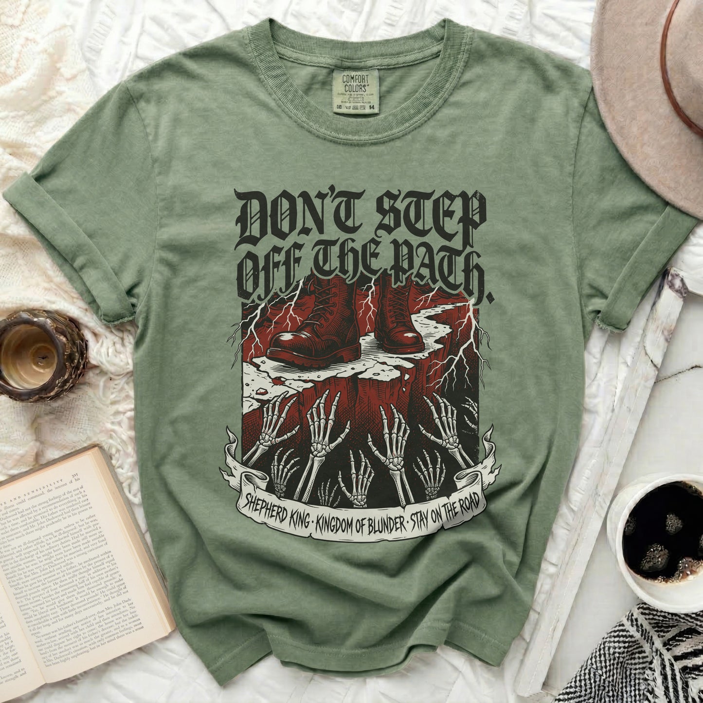 Olive green t-shirt with skull and hand graphic and text.