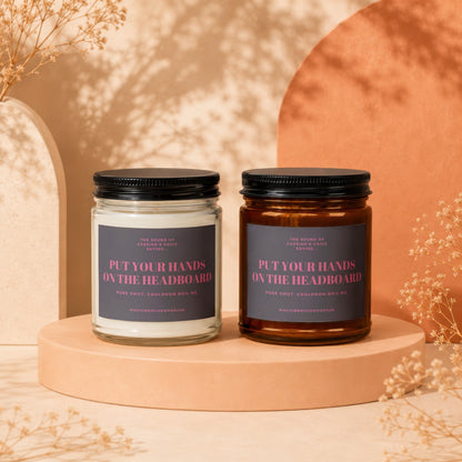 Two candles with labels that read "Put Your Hands On The Headboard".