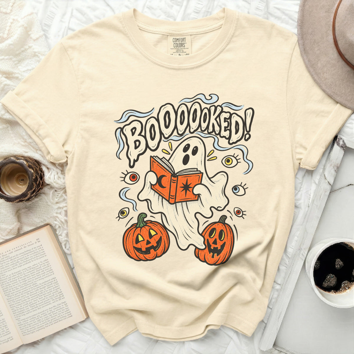 Ghost reading book with "BOOOOKED!" text and pumpkins.