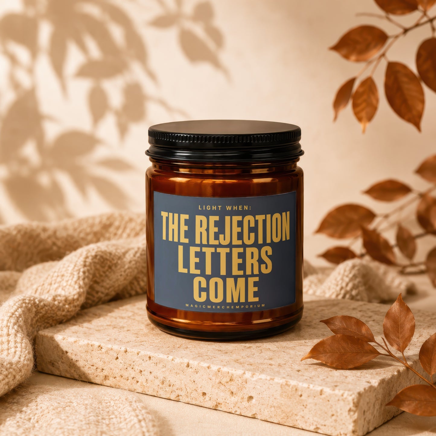 Amber jar candle with dark blue label reading "Light When: The Rejection Letters Come".