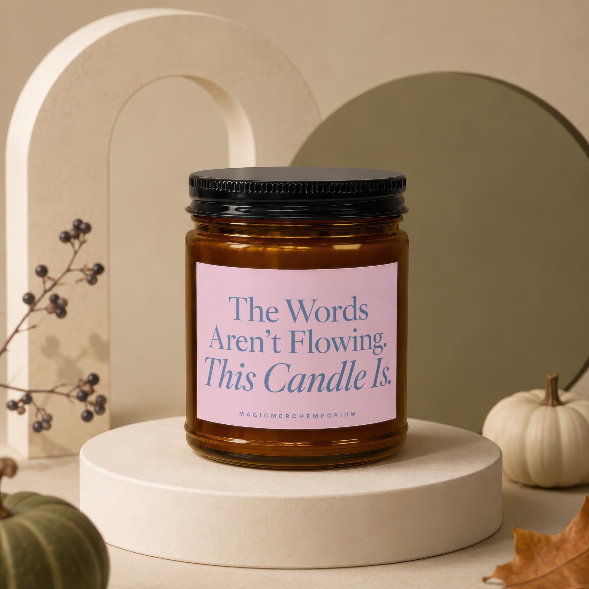 Amber candle with pink label reading "The Words Aren't Flowing. This Candle Is."