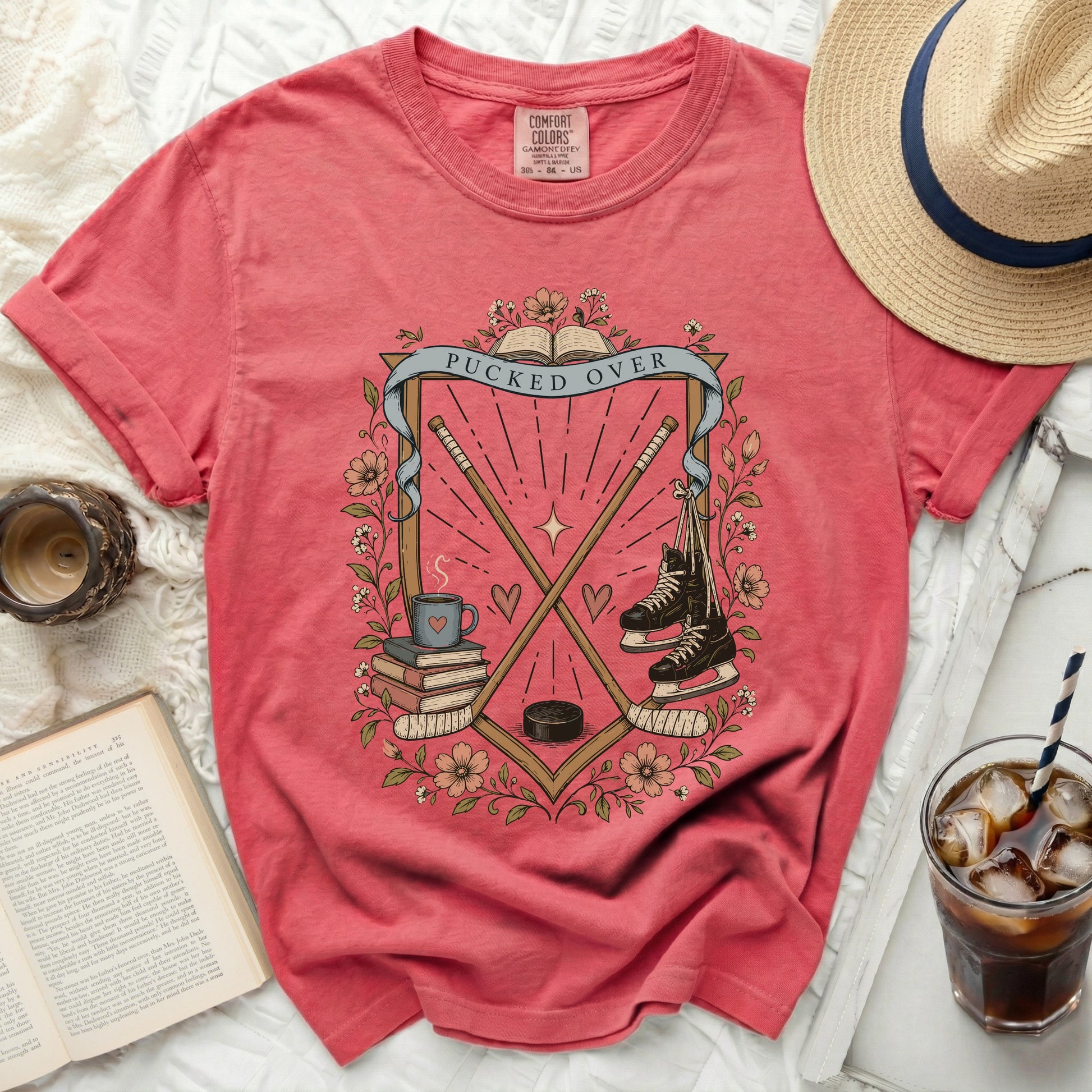 Coral t-shirt with hockey sticks, skates, books, and "Pucked Over" text.