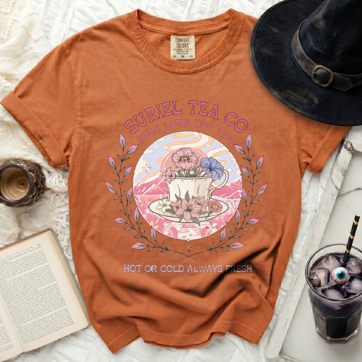 Orange t-shirt with Suriel Tea Co. graphic featuring teacup and flowers.