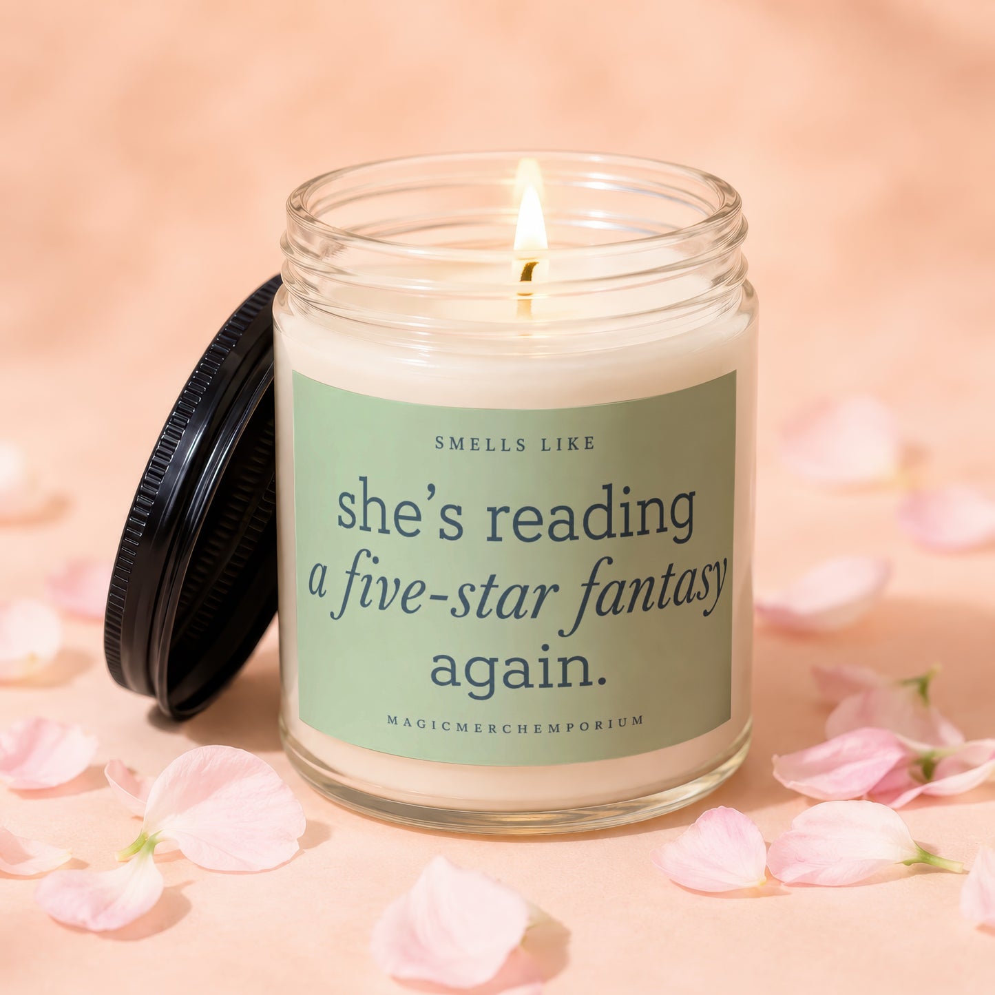 Lit candle in glass jar with text "she's reading a five-star fantasy again."