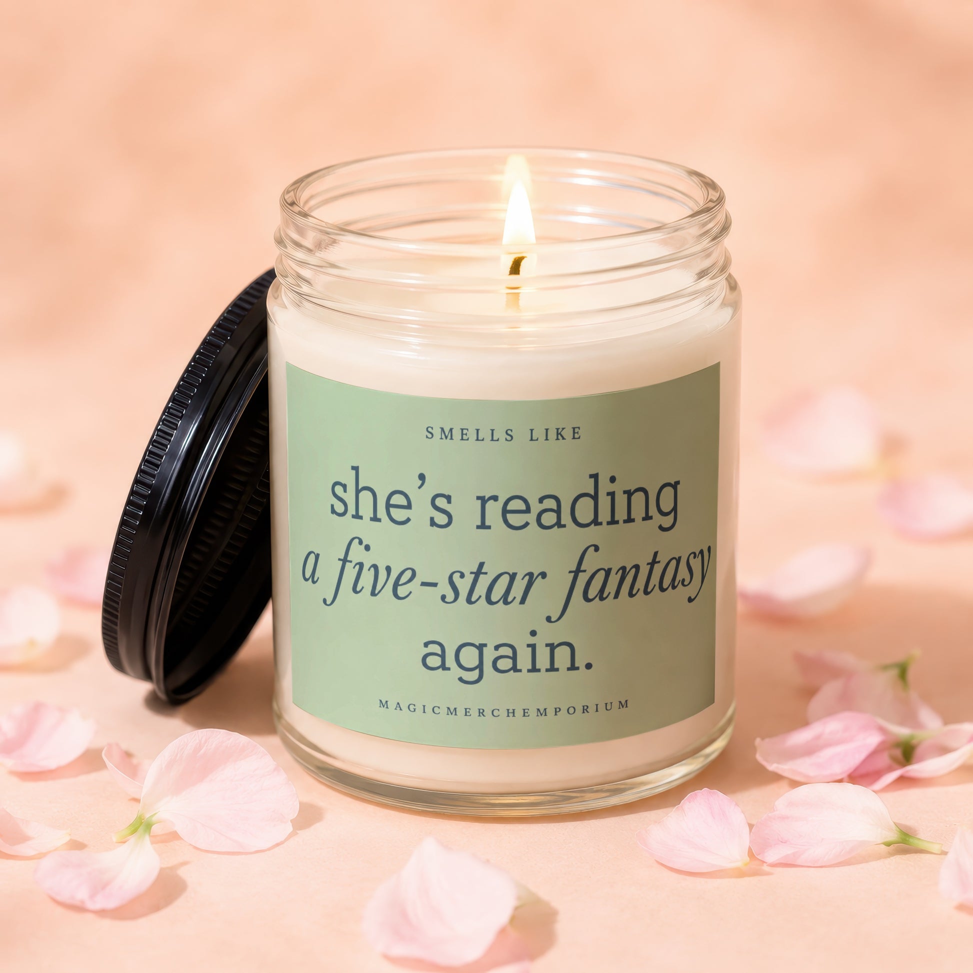 Lit candle in glass jar with text "she's reading a five-star fantasy again."