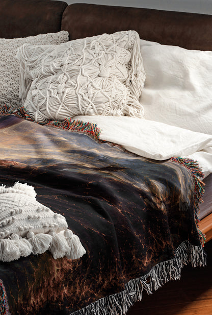 a cozy and inviting bedroom scene, featuring a bed with a dark blanket and white pillows, a brown leather couch, and a colorful throw blanket with fringe.