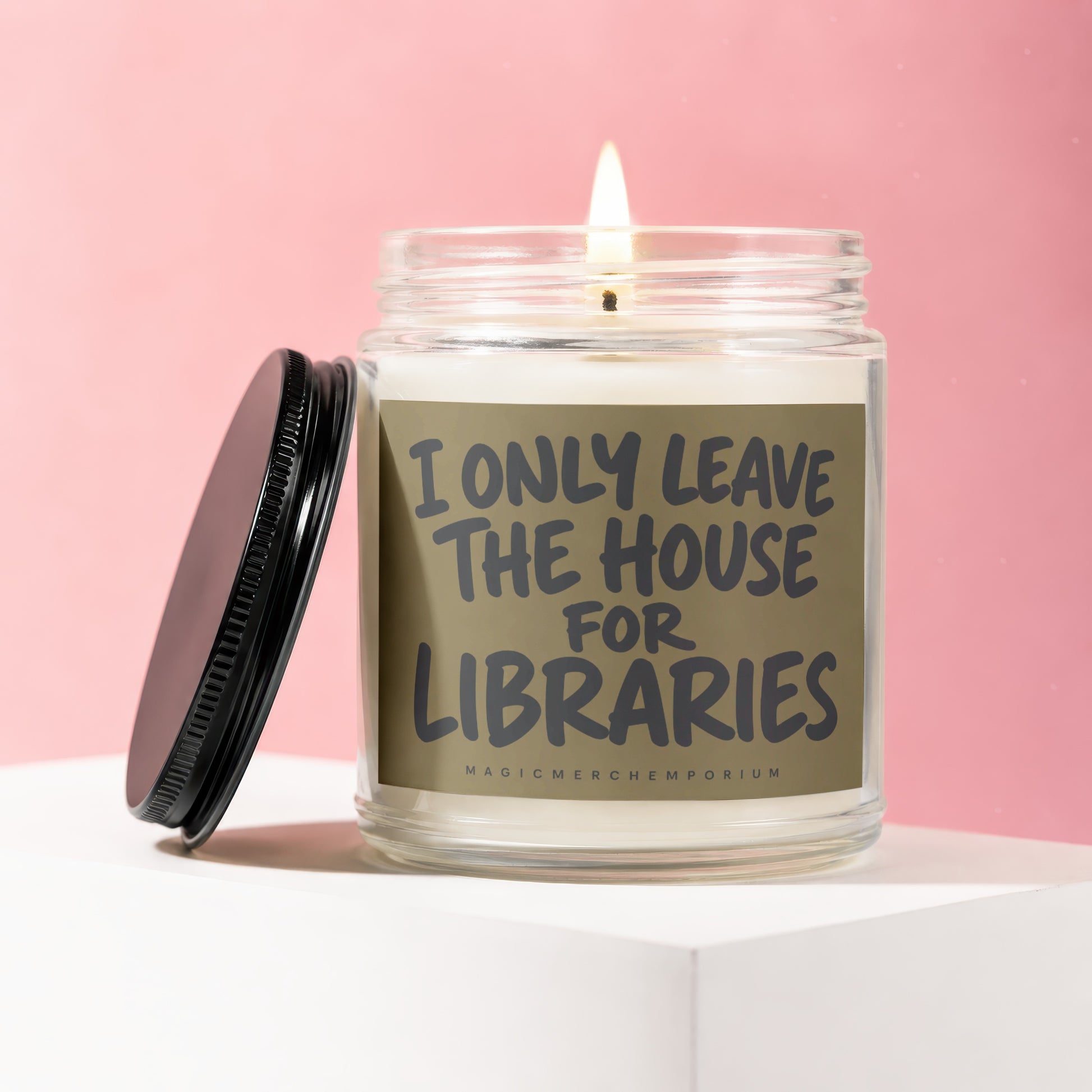 Glass candle with lit wick and "I only leave the house for libraries" text.