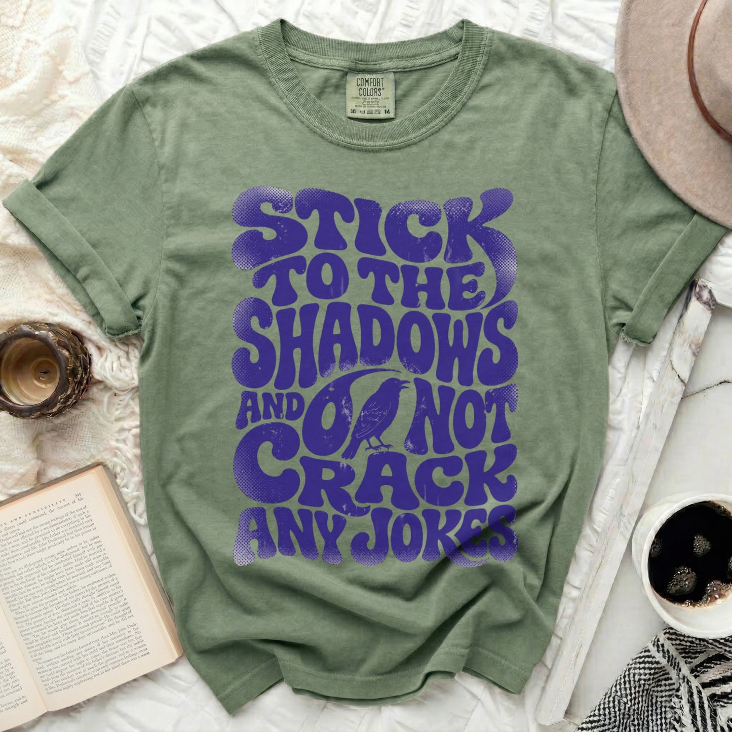 Green t-shirt with purple text "Stick to the shadows and do not crack any jokes."