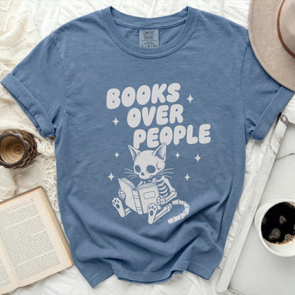 Comfort Colors blue t-shirt with white graphic of skeleton cat reading and text "BOOKS OVER PEOPLE".
