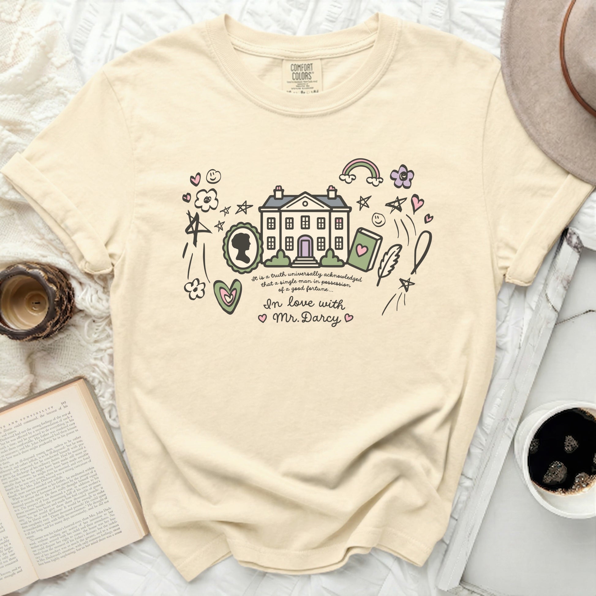 Cream t-shirt with illustrated house, book, cameo, hearts, rainbow, and "In love with Mr. Darcy."