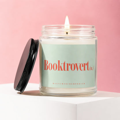 Glass candle with lit wick and "Booktrovert (n.)" on mint green label.