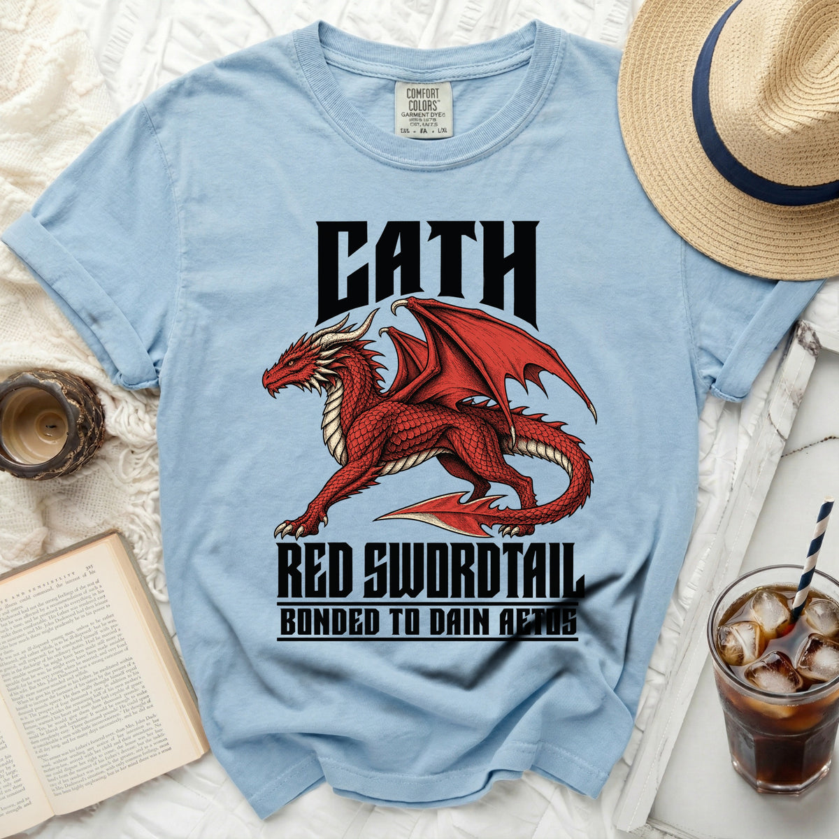 Light blue t-shirt with a red dragon graphic and text "CATH RED SWORDTAIL BONDED TO DAIN AETOS".