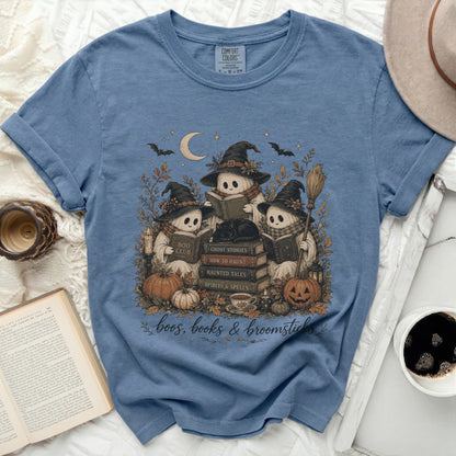 Three ghosts in witch hats read books surrounded by pumpkins and fall leaves.