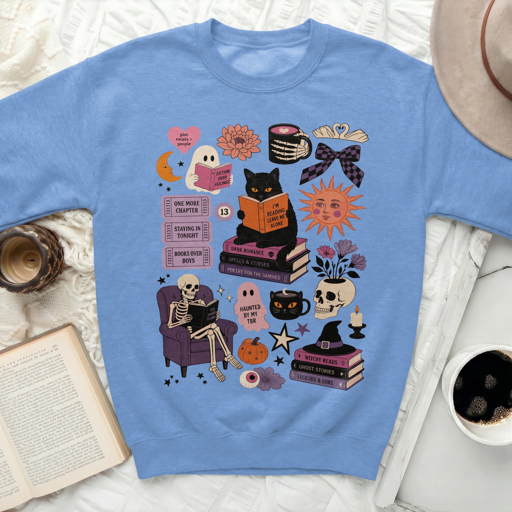 Blue sweatshirt with ghost, skeleton, cat, and book illustrations.