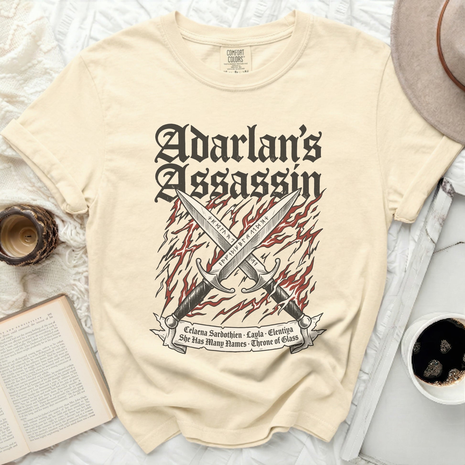 Cream t-shirt with crossed swords and "Adarlan's Assassin" text.