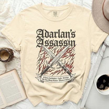 Cream t-shirt with crossed swords and "Adarlan's Assassin" text.
