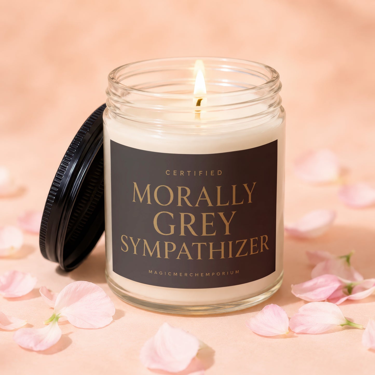 Lit scented candle in glass jar with black lid, "Morally Grey Sympathizer" and "MagicMerchEmporium" text.