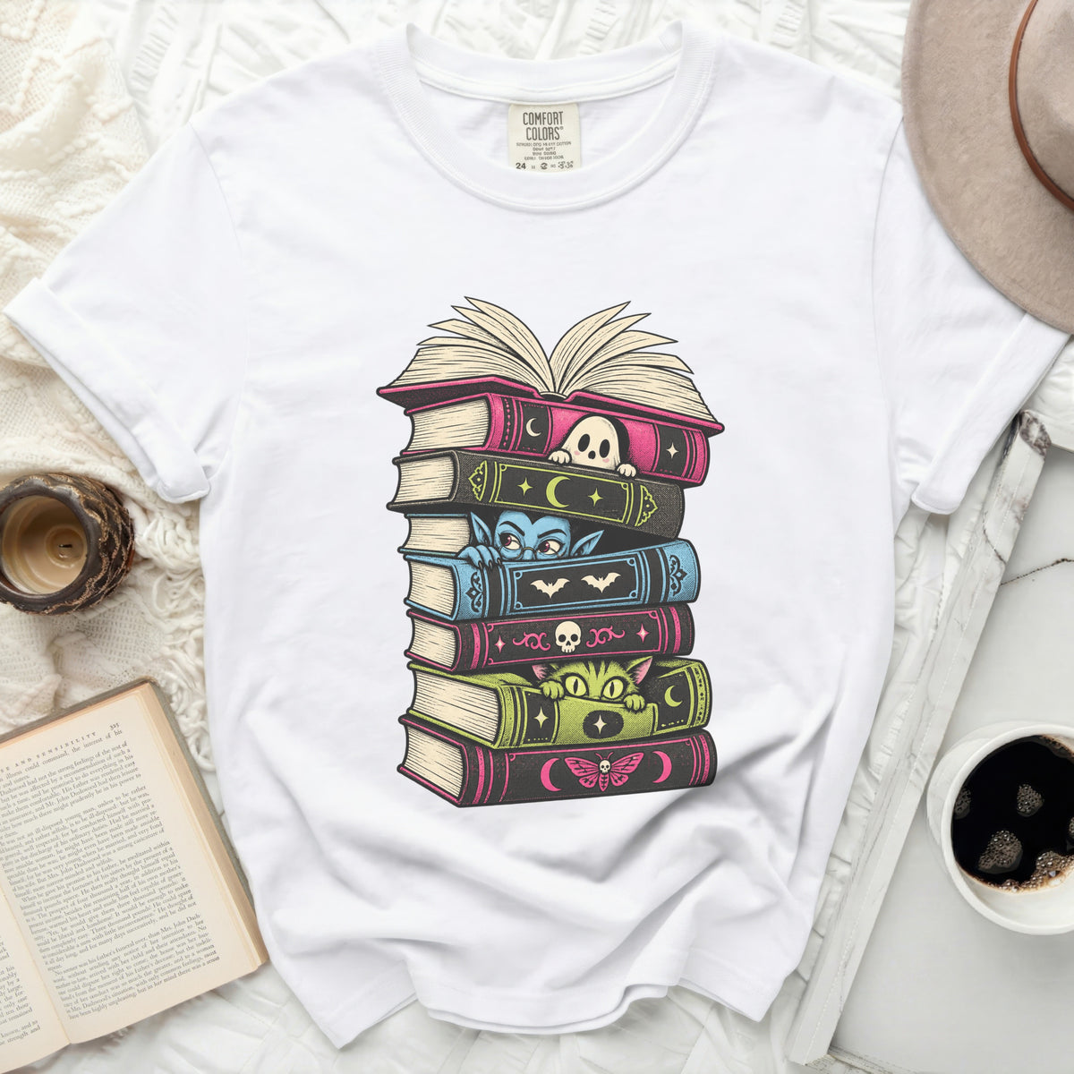 White t-shirt with a stacked book graphic featuring a ghost, vampire, cat, and butterfly.