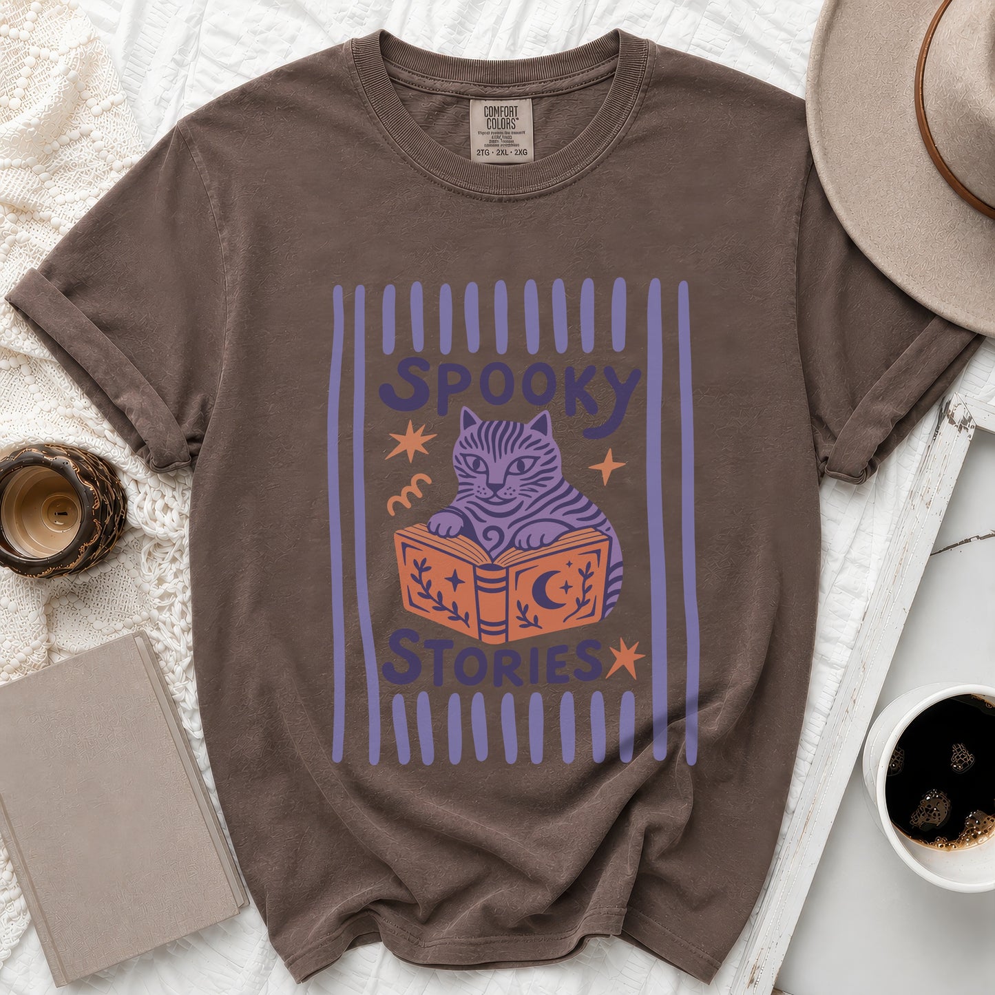 Brown t-shirt with a graphic of a cat reading a book with "Spooky Stories" text.