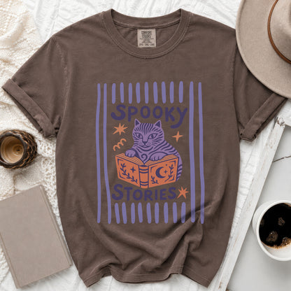 Brown t-shirt with a graphic of a cat reading a book with "Spooky Stories" text.