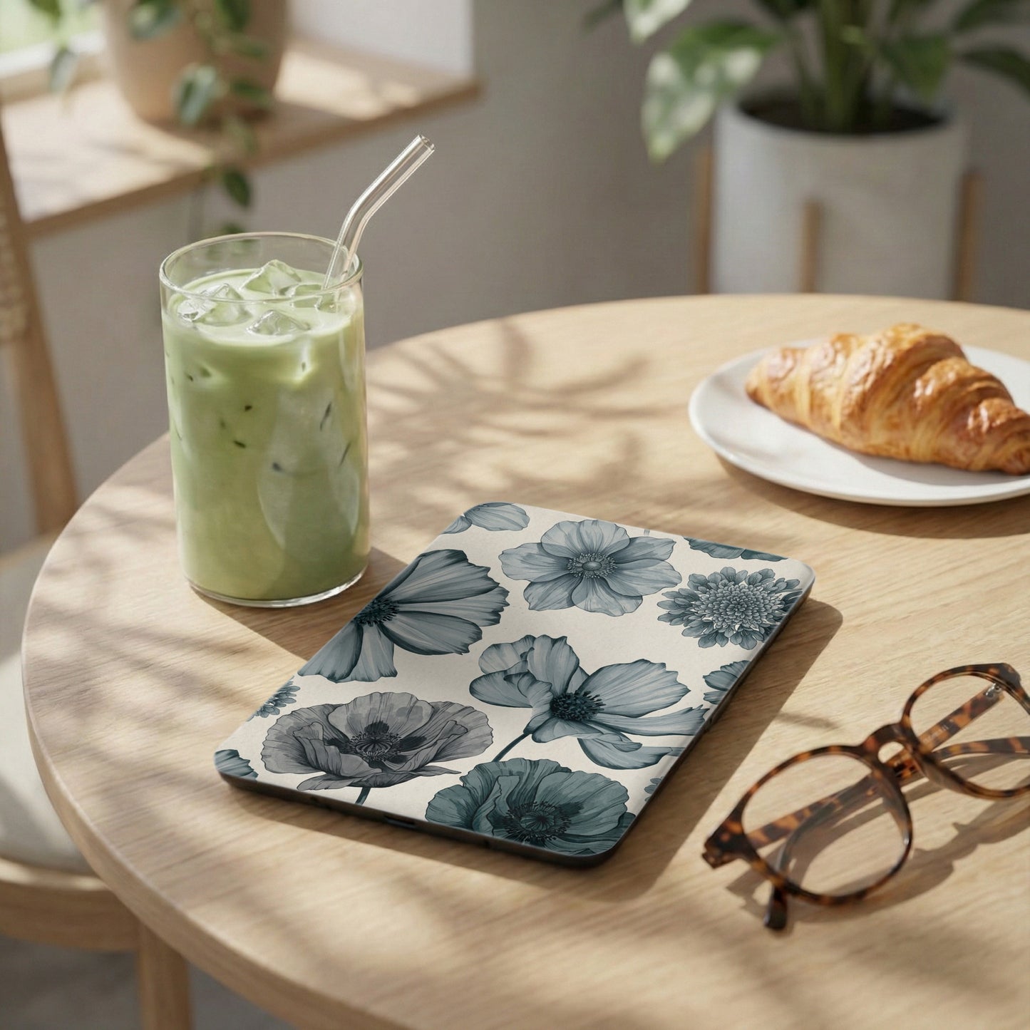 Floral patterned tablet case next to a matcha drink and croissant.
