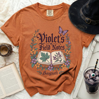 Orange t-shirt with "Violet's Field Notes Basgiath" text and floral design.