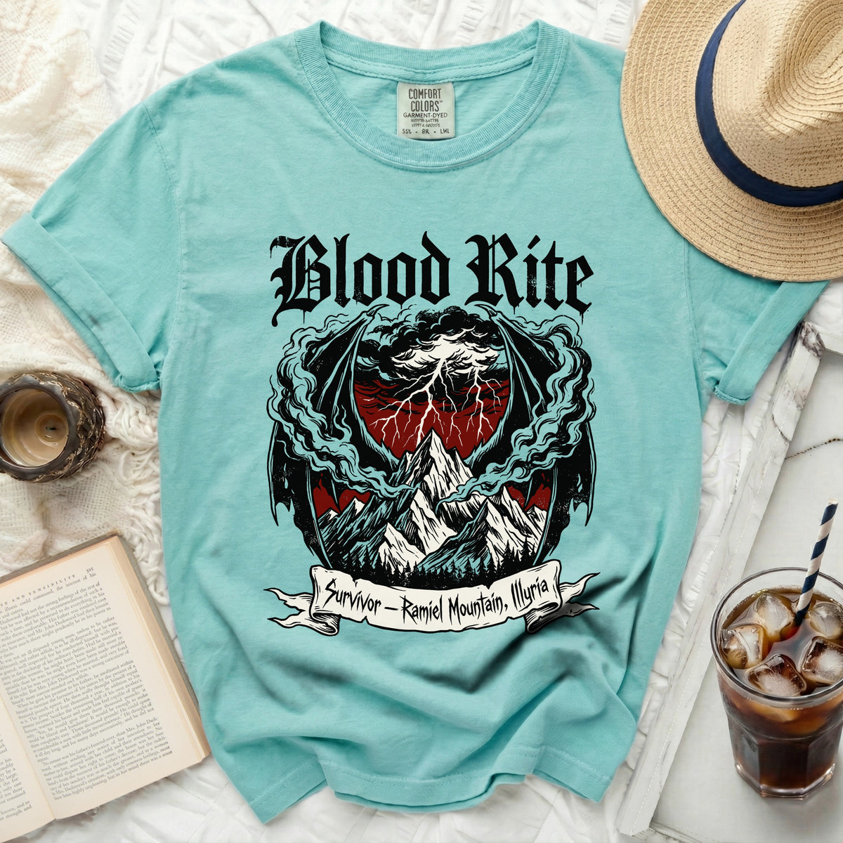 Teal t-shirt with "Blood Rite" and dragon wings over mountains graphic.