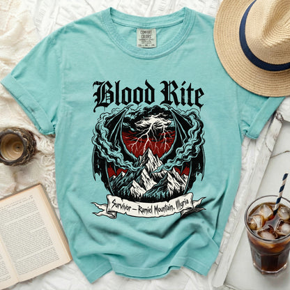 Teal t-shirt with "Blood Rite" and dragon wings over mountains graphic.