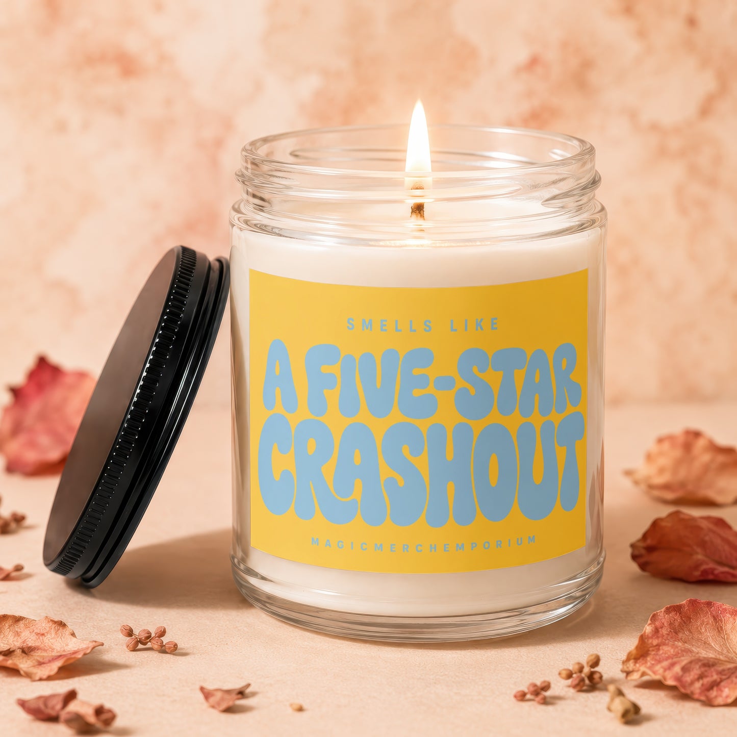Lit candle with yellow label reading "Smells Like A Five-Star Crashout".