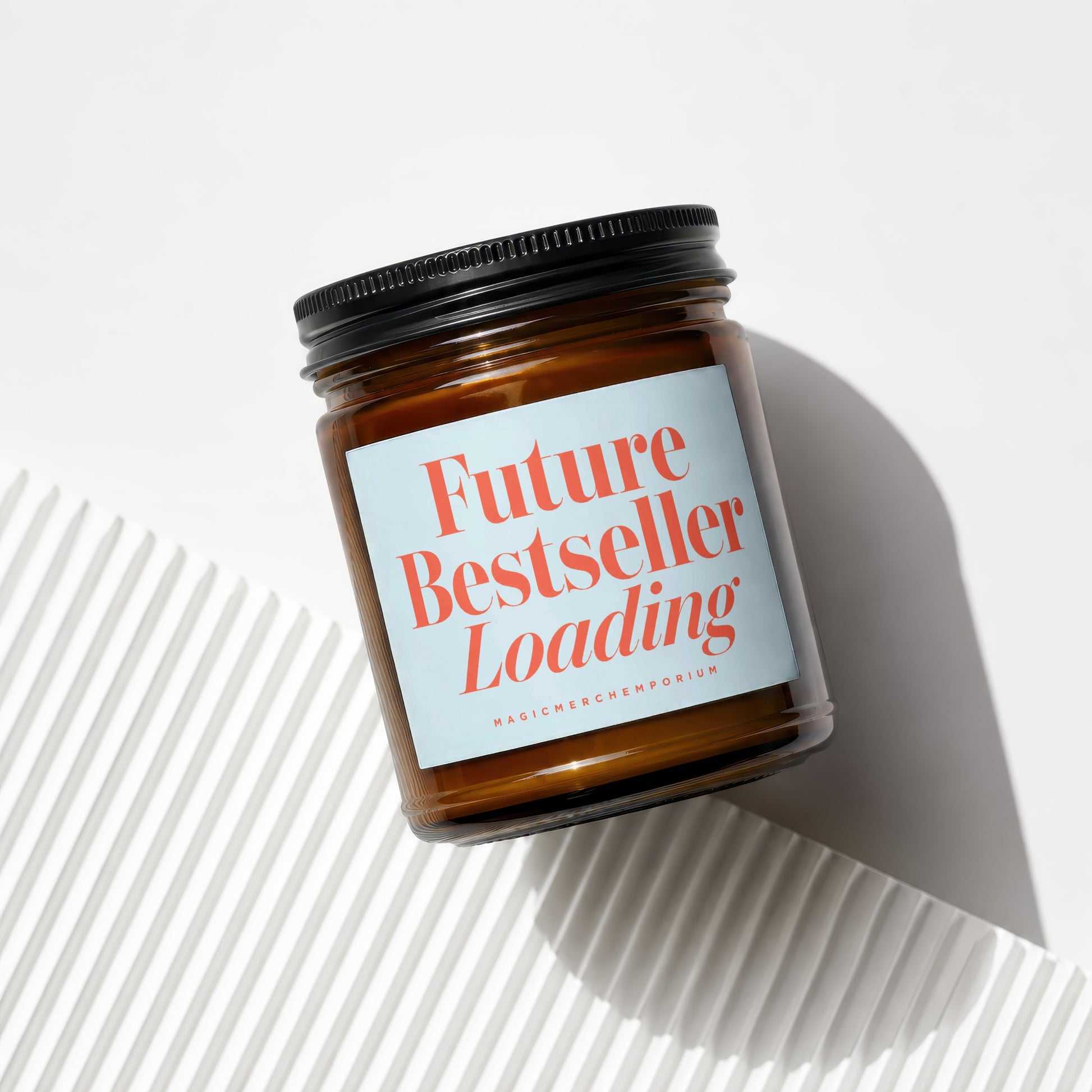 Amber candle in glass jar with black lid and blue label that reads "Future Bestseller Loading".