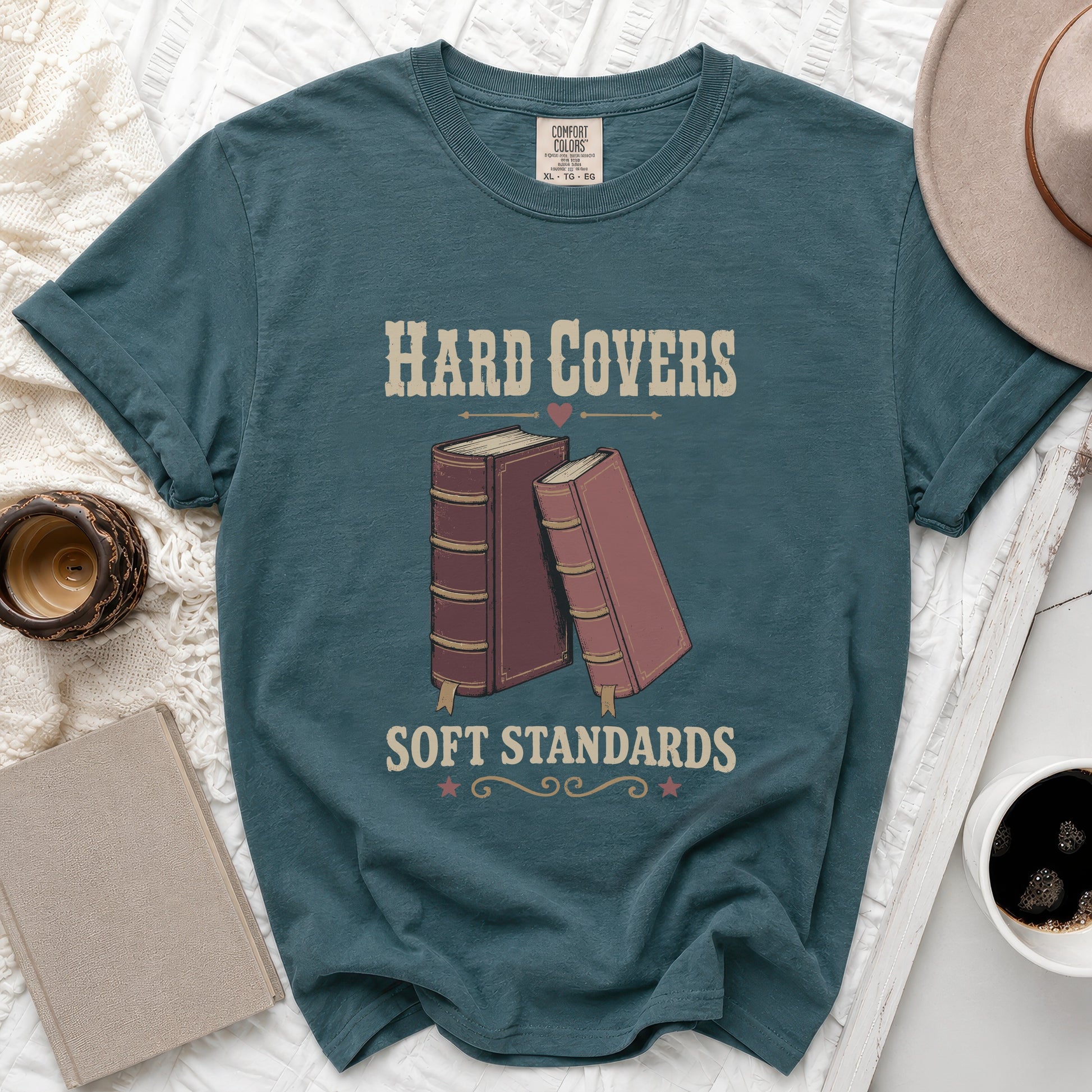 Teal t-shirt with "Hard Covers Soft Standards" text and book graphic.