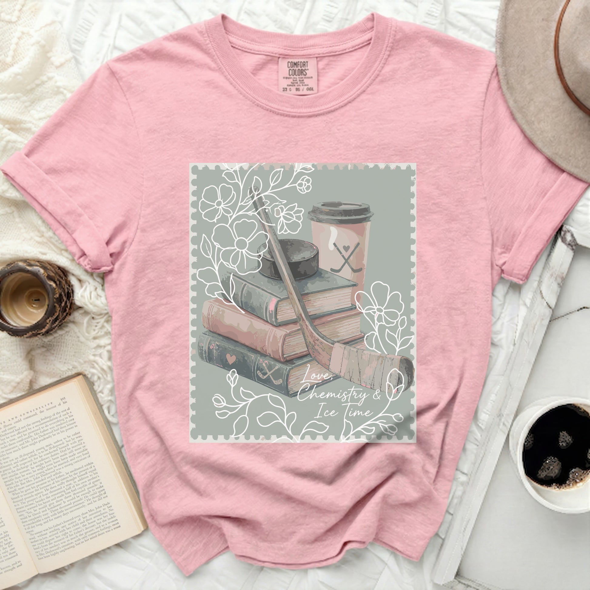 Pink t-shirt with a stamp graphic of hockey puck, stick, and coffee.