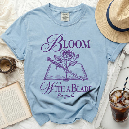 Light blue t-shirt with purple text "Bloom With a Blade Basgiath" and rose/dagger design.