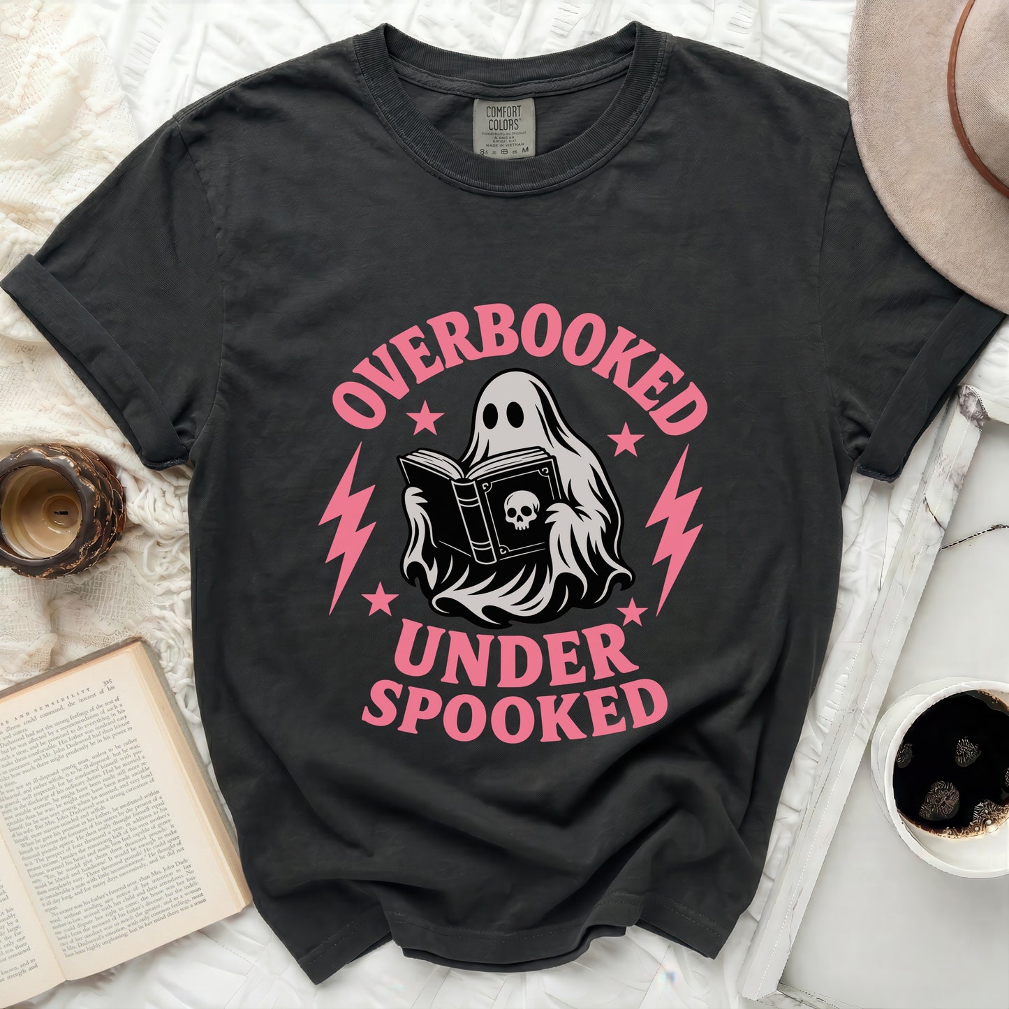Black t-shirt with a ghost reading a book and text "OVERBOOKED UNDER SPOOKED".