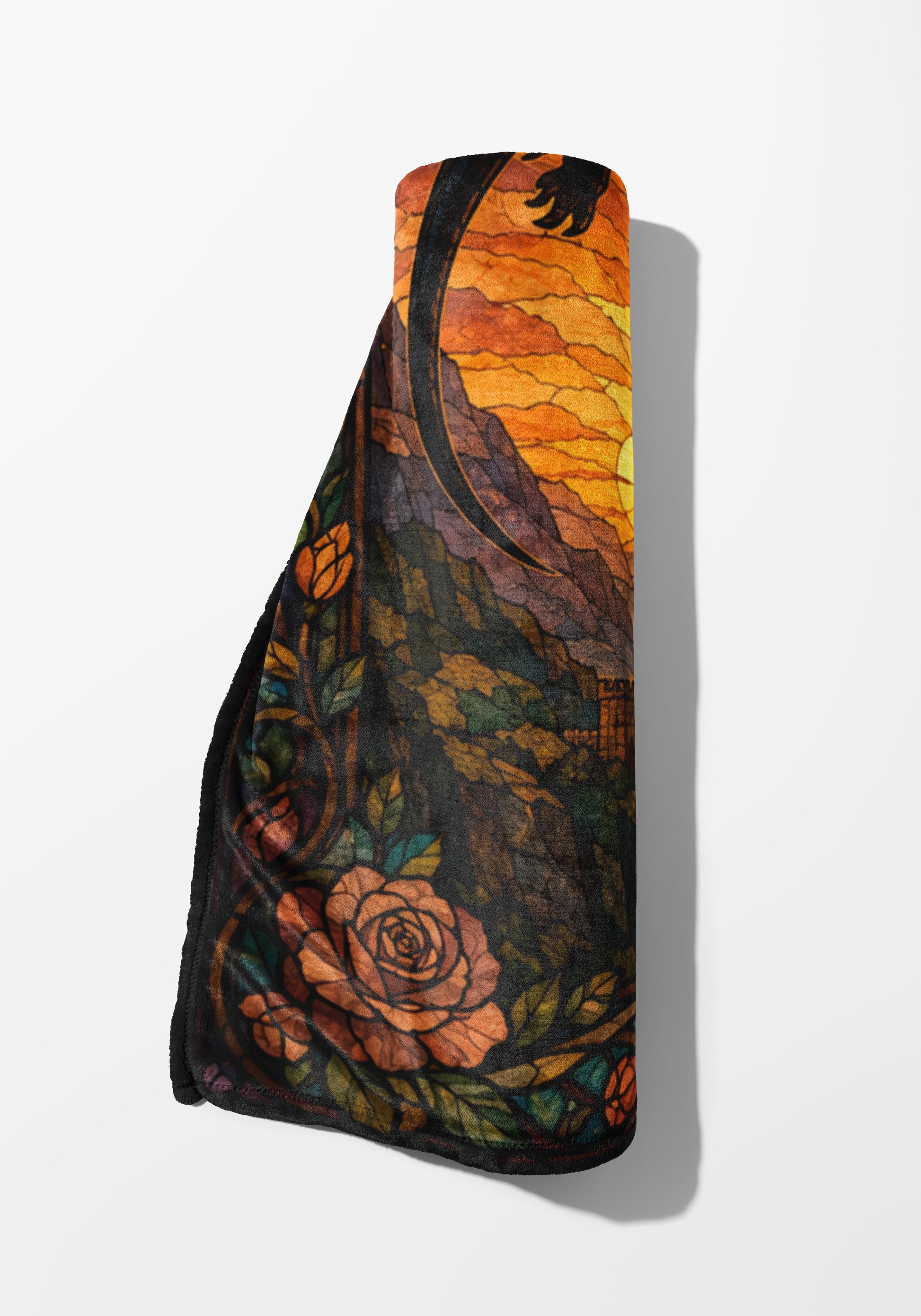 Rolled blanket with stained-glass style sunset, mountains, roses, and vine pattern.