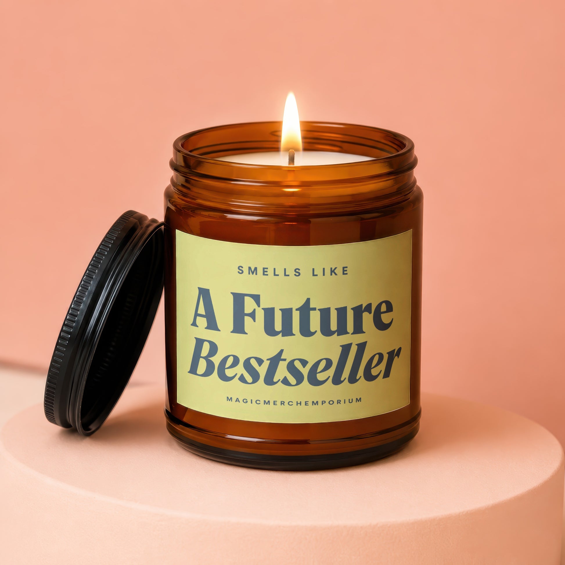 Candle in amber jar with lid off, lit flame, with text "SMELLS LIKE A Future Bestseller".