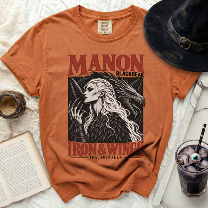 Orange t-shirt with Manon Blackbeak Iron & Wings graphic and witch hat.
