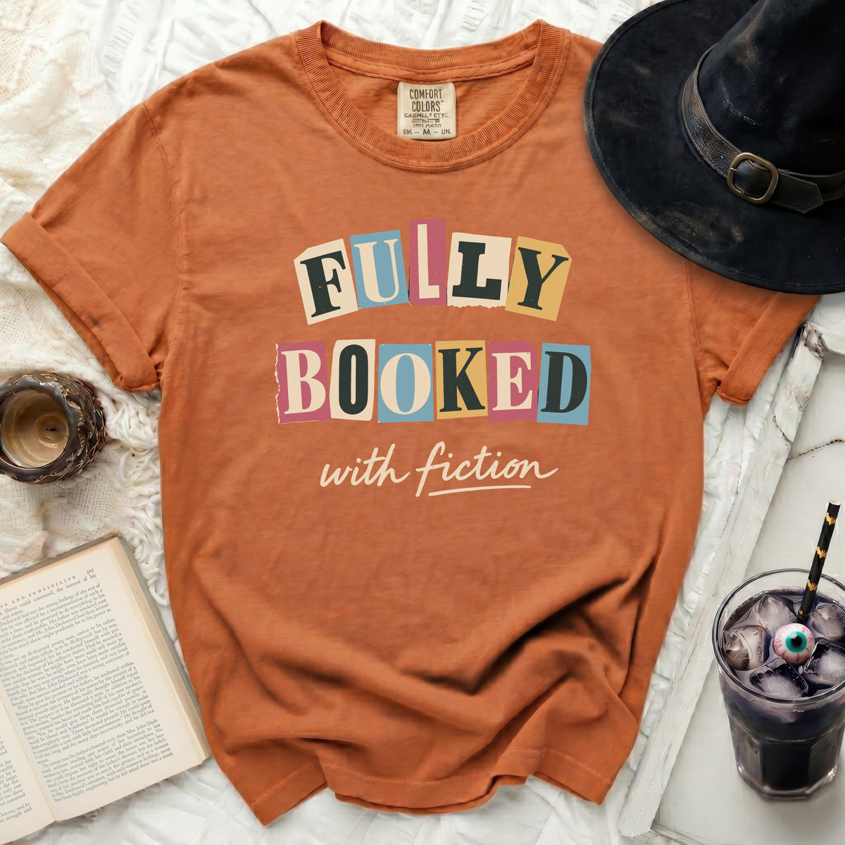 Orange t-shirt with "FULLY BOOKED with fiction" graphic.