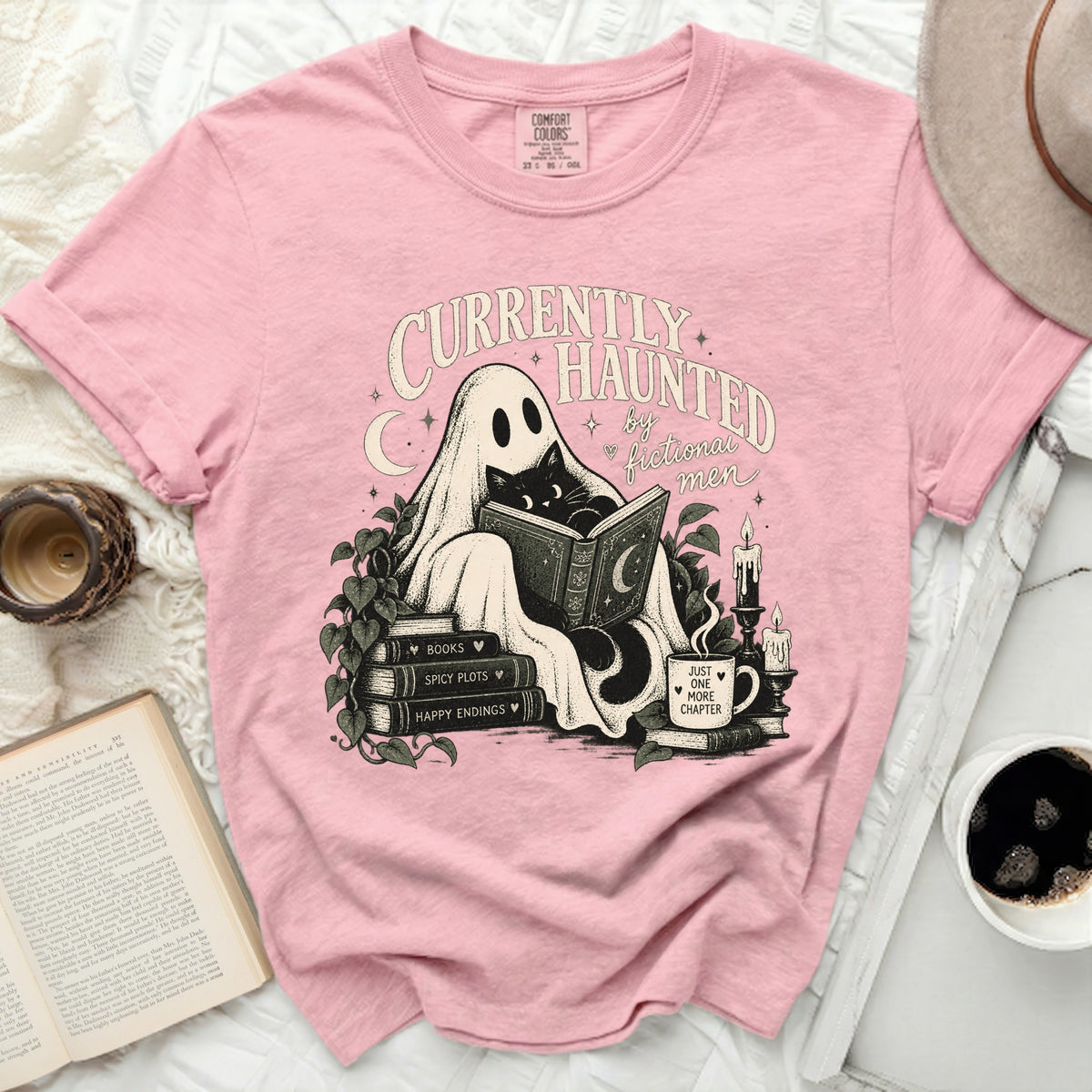 Pink t-shirt with a graphic of a ghost reading to a cat and text "Currently Haunted by Fictional Men".