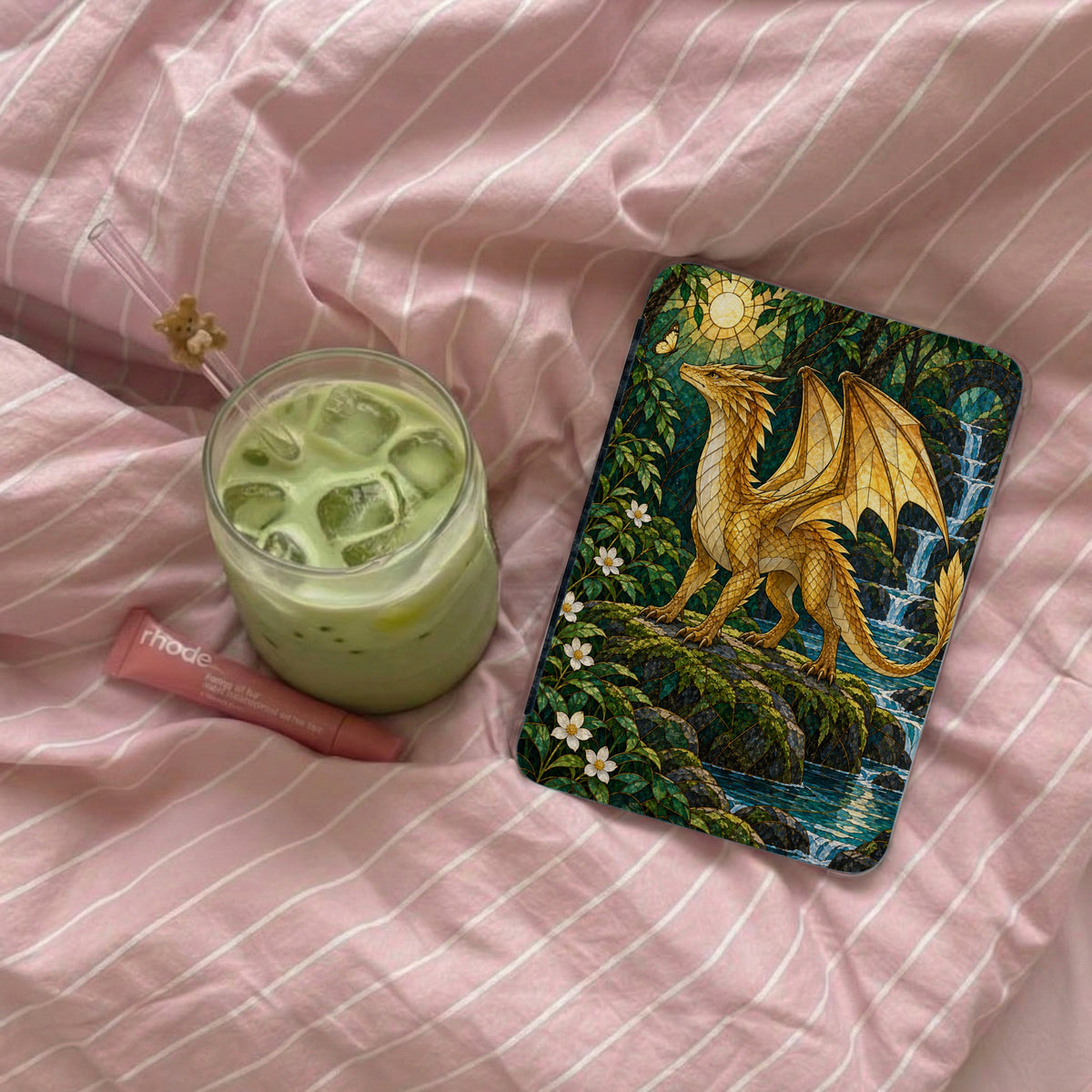 Golden dragon perched on rocks beside waterfall, with green drink and lip balm.