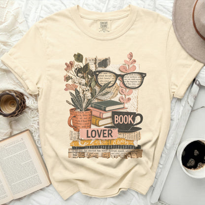 Cream t-shirt with "BOOK LOVER" text and stacked books, glasses, and flowers.