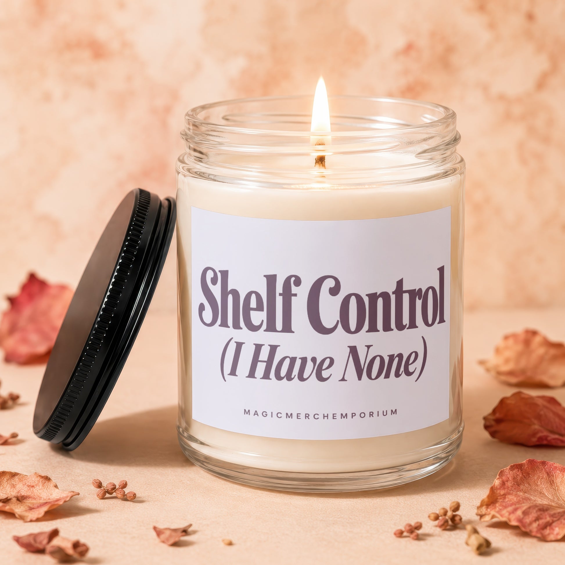Glass jar candle with lit wick and label reading "Shelf Control (I Have None)".