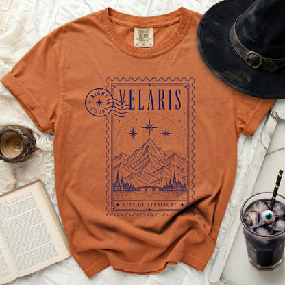 Orange t-shirt with "Velaris City of Starlight" graphic in a postage stamp design.