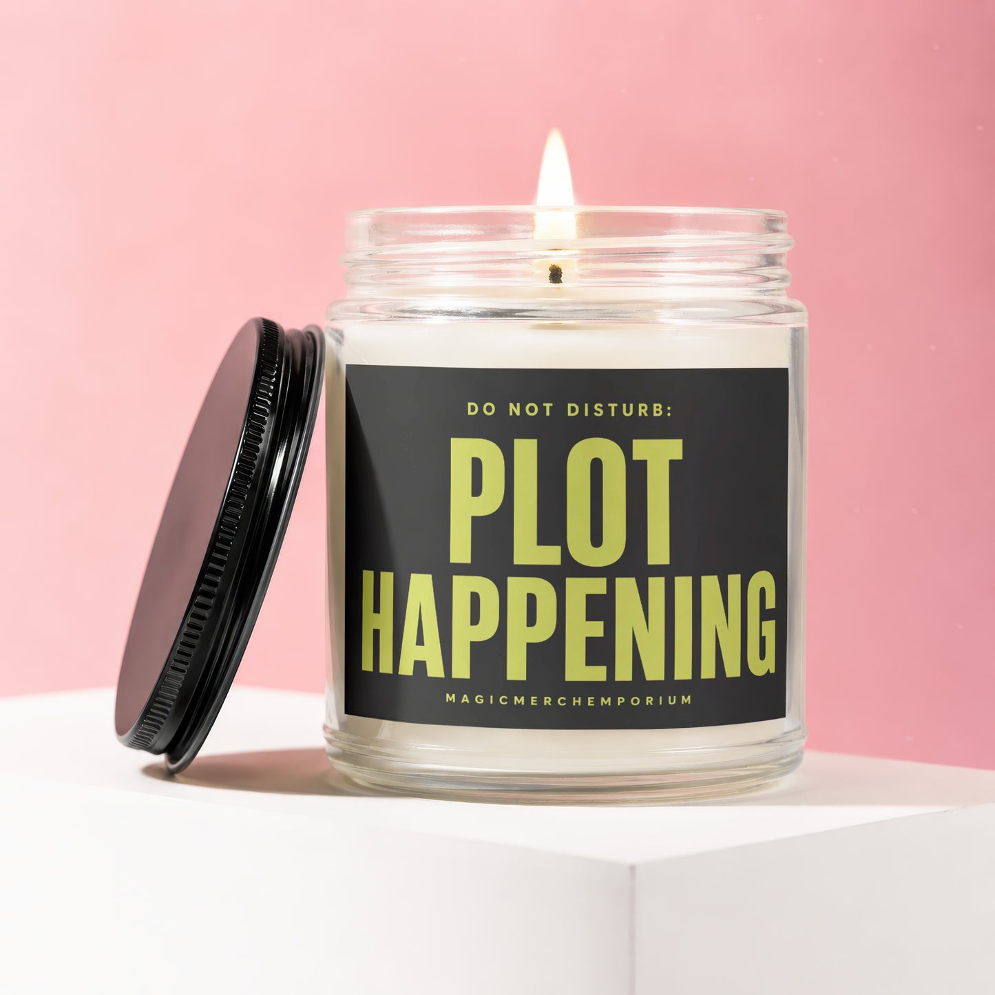 Lit candle in glass jar with black lid, reading "DO NOT DISTURB: PLOT HAPPENING".