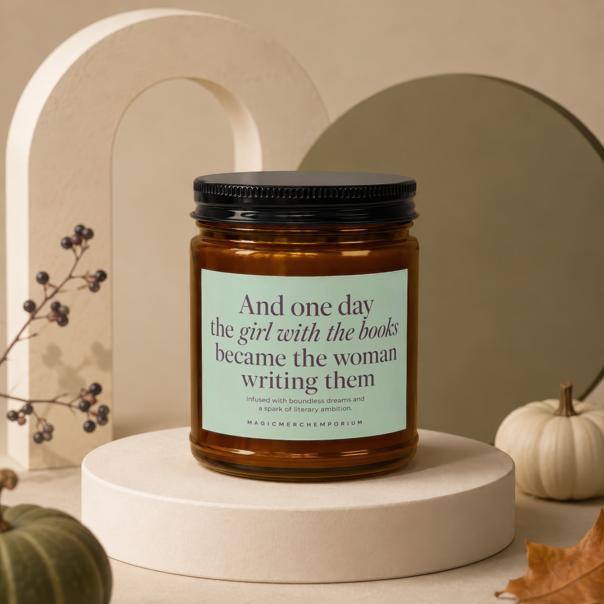 Amber jar candle with black lid featuring text: "And one day the girl with the books became the woman writing them".